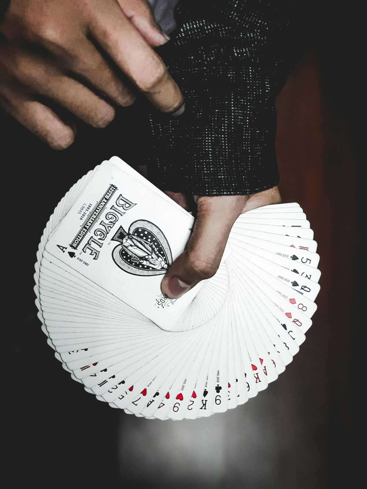 Detailed view of a hand displaying a fan of playing cards indoors, focusing on leisure and card games.